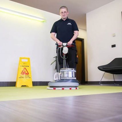 Man in Flawless Cleaning Ltd uniform washing a green office carpet